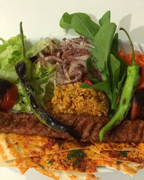 Adana kebap, bulgur pilavı ve yeşilliklerle