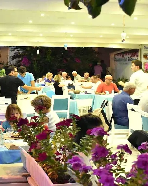 Akşam, misafirlerle dolu restoran terası ve begonviller